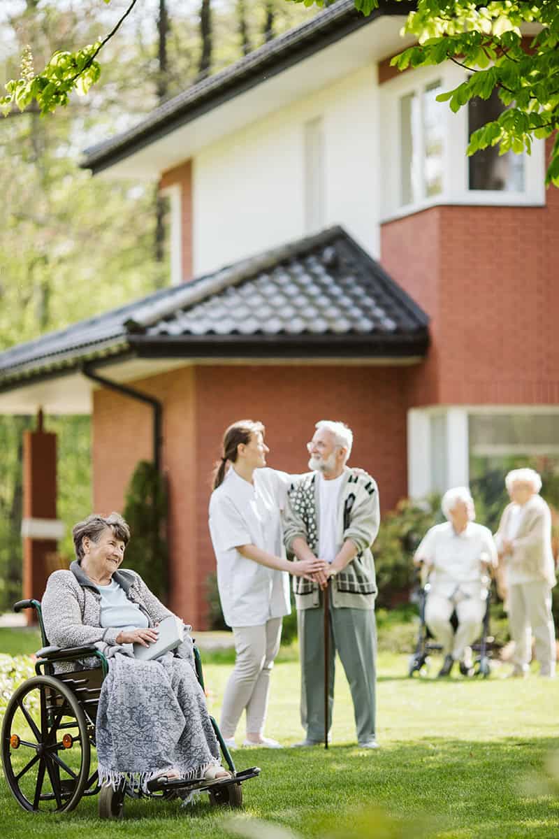 Elderly individuals interacting with a caregiver outdoors showcasing assistance under adult guardianship.